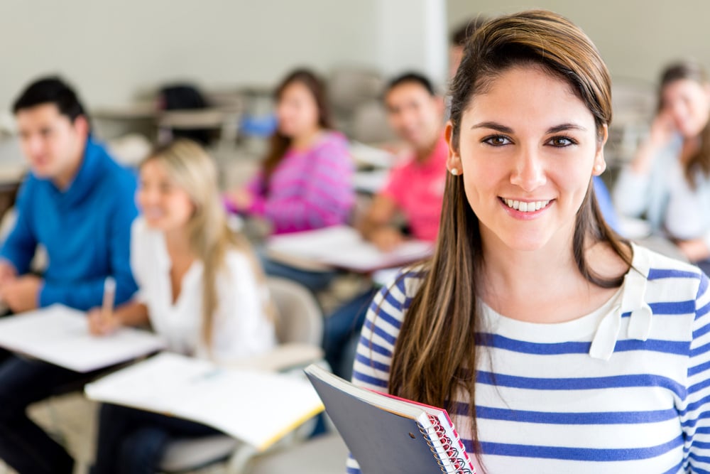 Female college student in a classroom holding a notebook